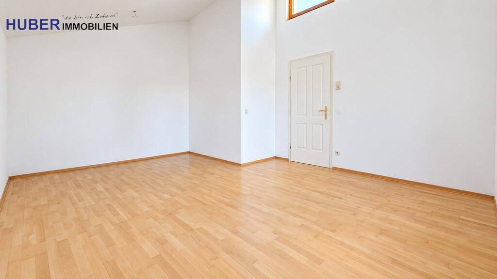Helles, leeres Zimmer mit hoher Decke und schönem Holzboden, bereit zur Einrichtung.