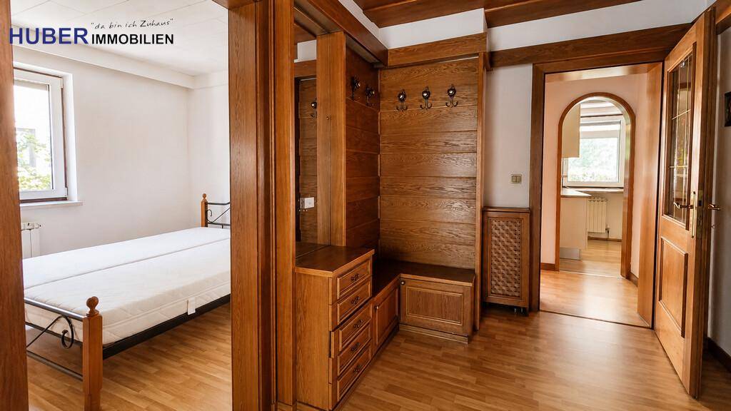 Gemütlicher Flur mit Holzvertäfelung, Garderobe und Zugang zu einem Schlafzimmer.