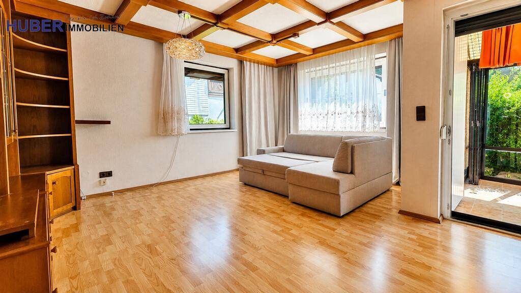 Geräumiges Wohnzimmer mit Holzbalkendecke, Laminatboden und Zugang zu einem Wintergarten.