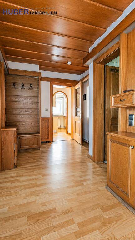 Geräumiger Flur mit Holzdecke, Laminatboden und Garderobe, die zu weiteren Räumen führt.