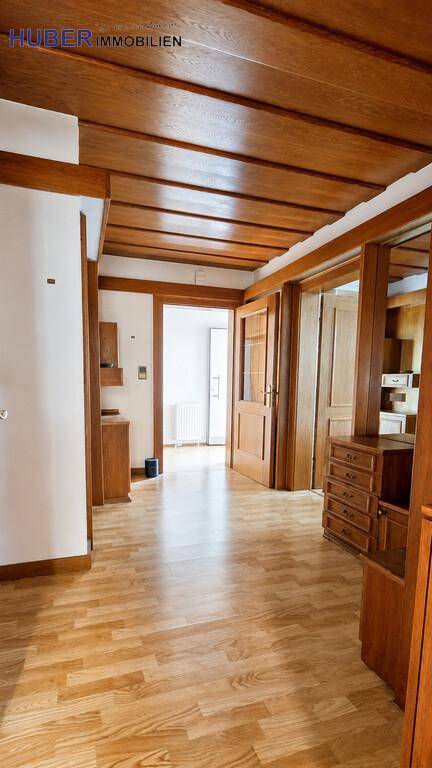 Geräumiger Flur mit Holzdecke, Laminatboden und Garderobe, die zu weiteren Räumen führt.