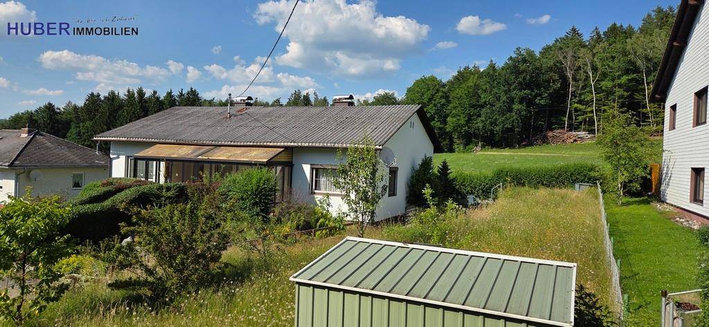 Einfamilienhaus mit Wintergarten und großem Gartenbereich, umgeben von Natur.