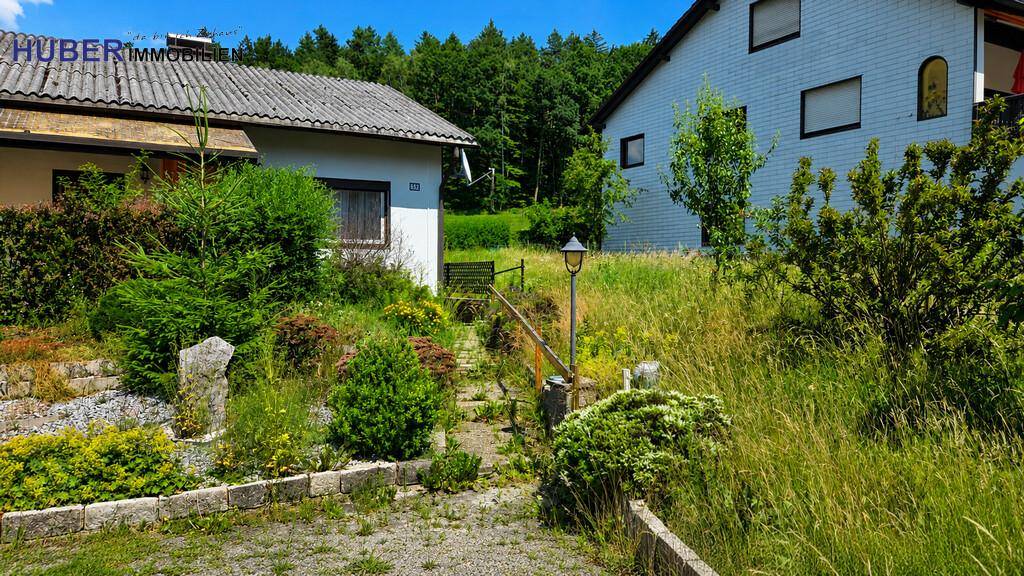 Steinweg führt durch den grünen Vorgarten zu einem weiteren Gebäude in ländlicher Umgebung.