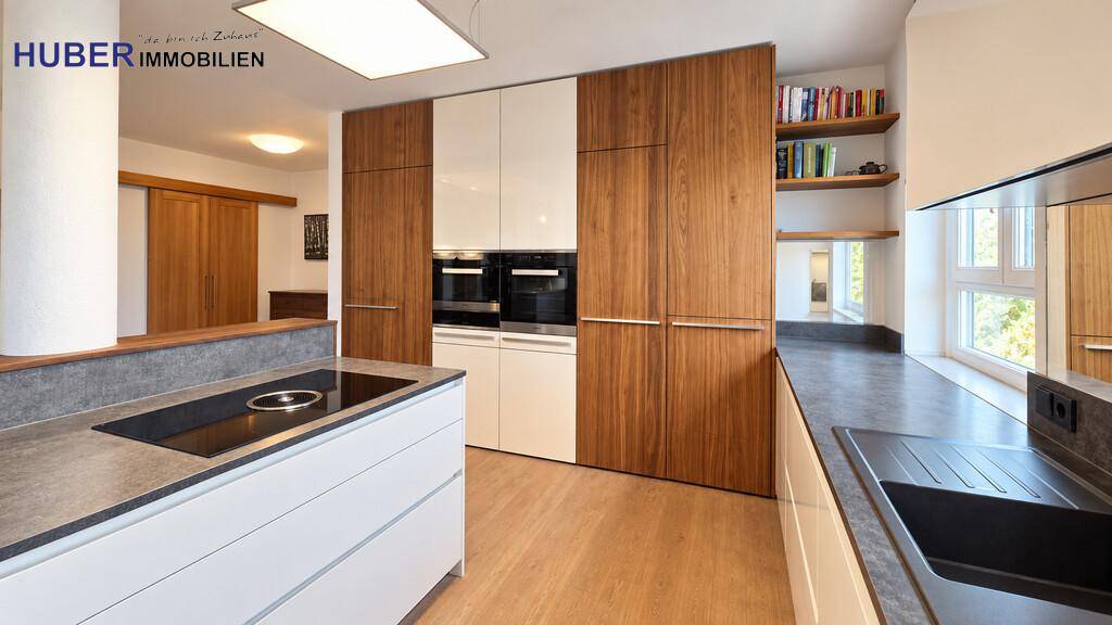 Stilvolle Küche mit Holz- und weißen Fronten, integrierten Backöfen und Kochfeld.