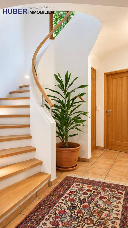 Heller Flur mit eleganter Holzwendeltreppe und dekorativem Teppich auf Fliesenboden.