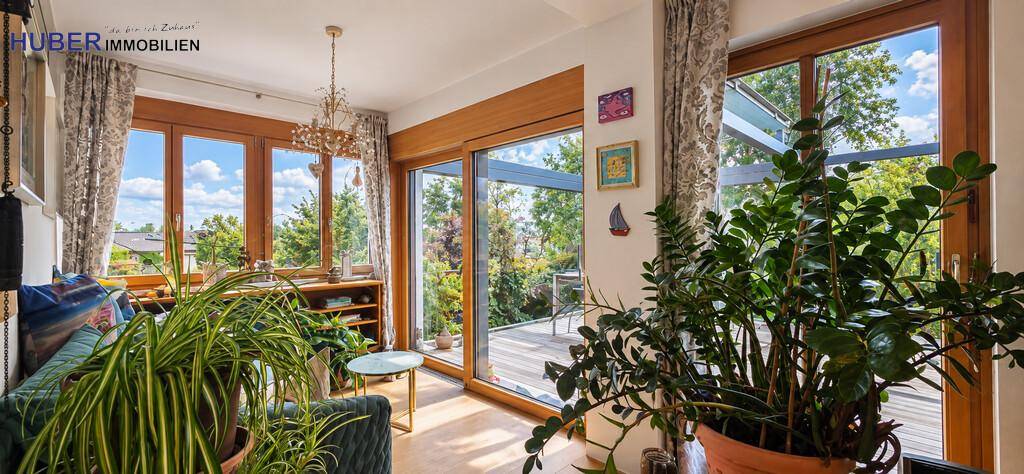 Helles Wohnzimmer mit großen Glasfronten, die den Blick ins Grüne freigeben.