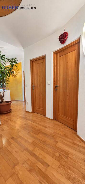 Geräumiger Flur mit Holztüren und Parkettboden, der zu einem weiteren Raum führt.