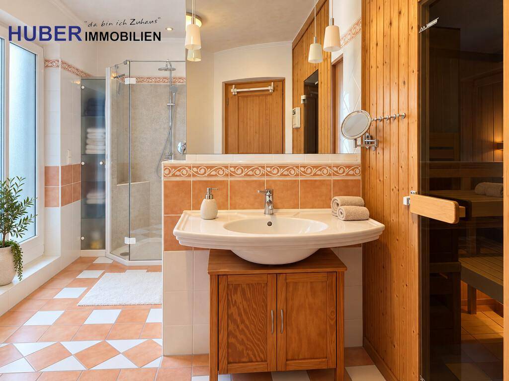 Geräumiges Badezimmer mit Dusche, Waschbecken und integrierter Sauna, ausgestattet mit warmen Holzelementen und Fliesen.
