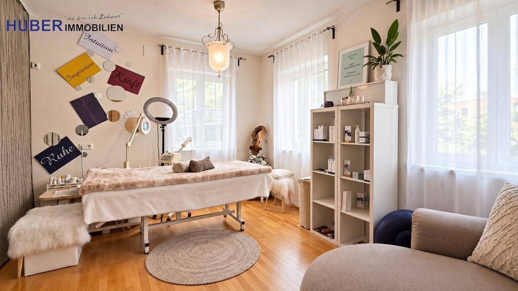 Vielseitiger Raum mit Behandlungsliege, Regalen und großen Fenstern, ideal für Wellness oder Hobby.