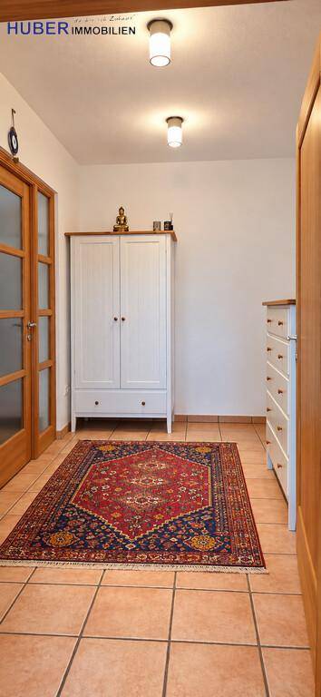 Heller Flur mit Fliesenboden, weißem Schrank und traditionellem Teppich, einladend gestaltet.