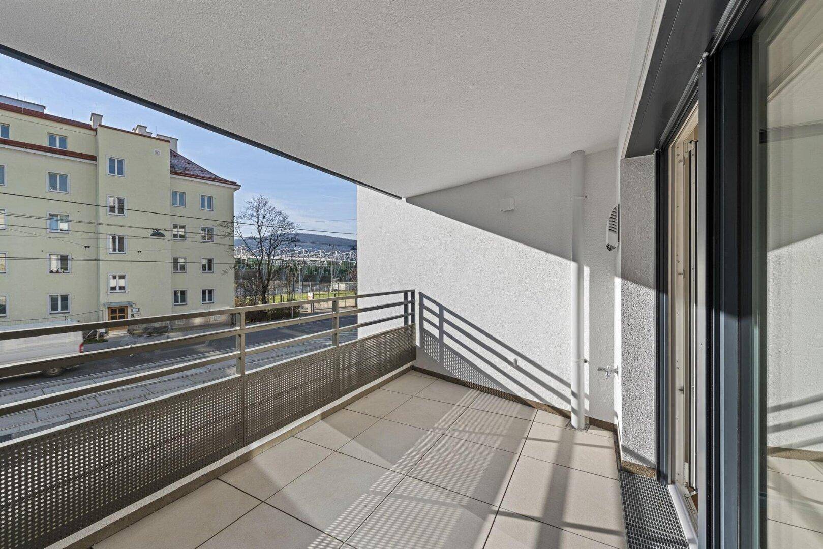 Moderner Balkon mit Fliesenboden und Metallgeländer, bietet einen weiten Blick auf die Umgebung.