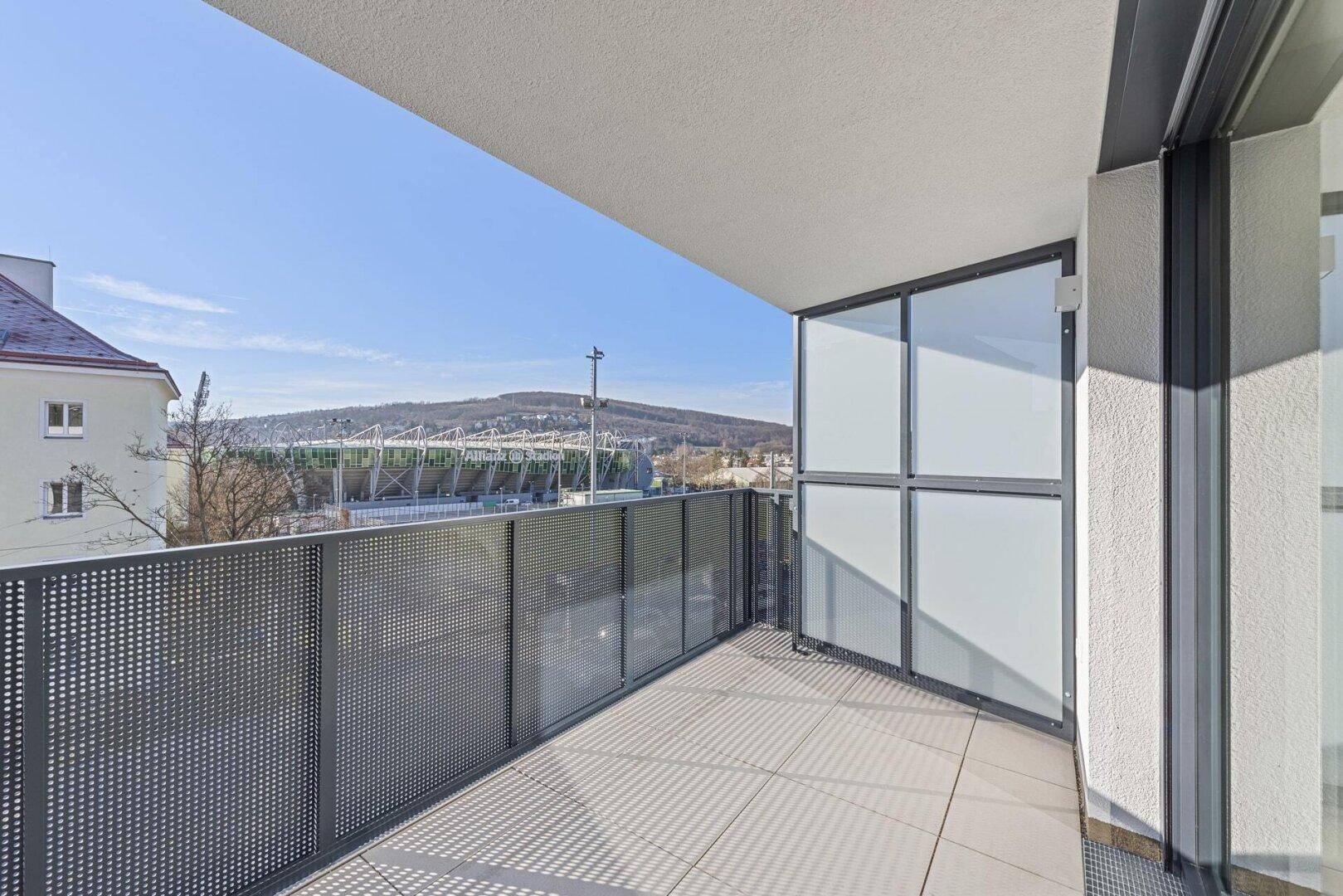 Geräumiger Balkon mit Fliesenboden und Blick auf die Umgebung und ein Stadion.