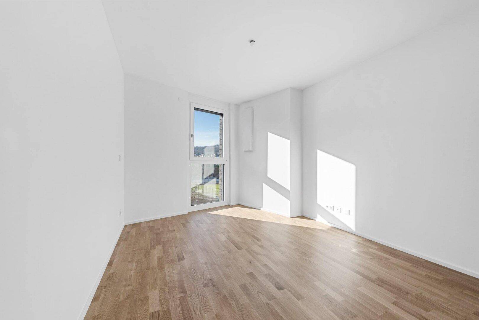 Sonniger Raum mit Parkettboden und Eckfenster, ideal als Schlafzimmer oder Arbeitszimmer.