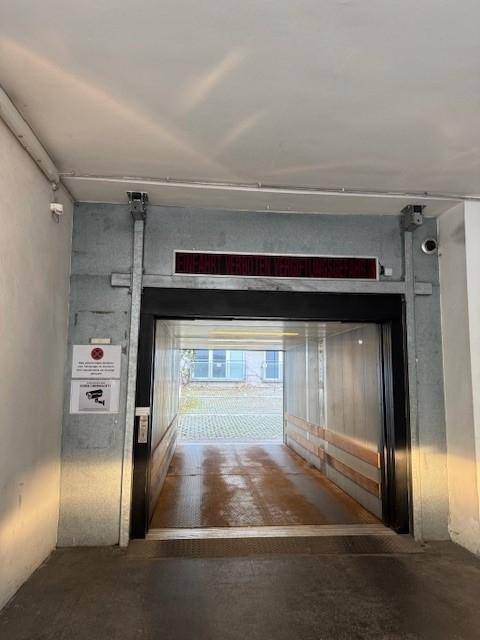 Offener Lastenaufzug in einer Tiefgarage mit Blick auf den Außenbereich und installierten Überwachungskameras.