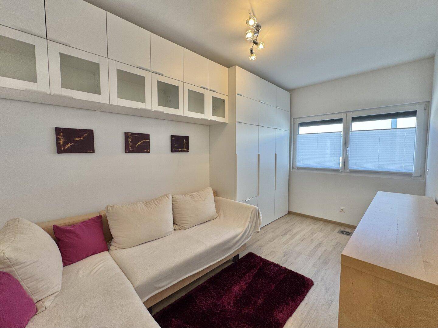 Gemütliches Zimmer mit Sofa, viel Stauraum durch Wandschränke und hellem Laminatboden.