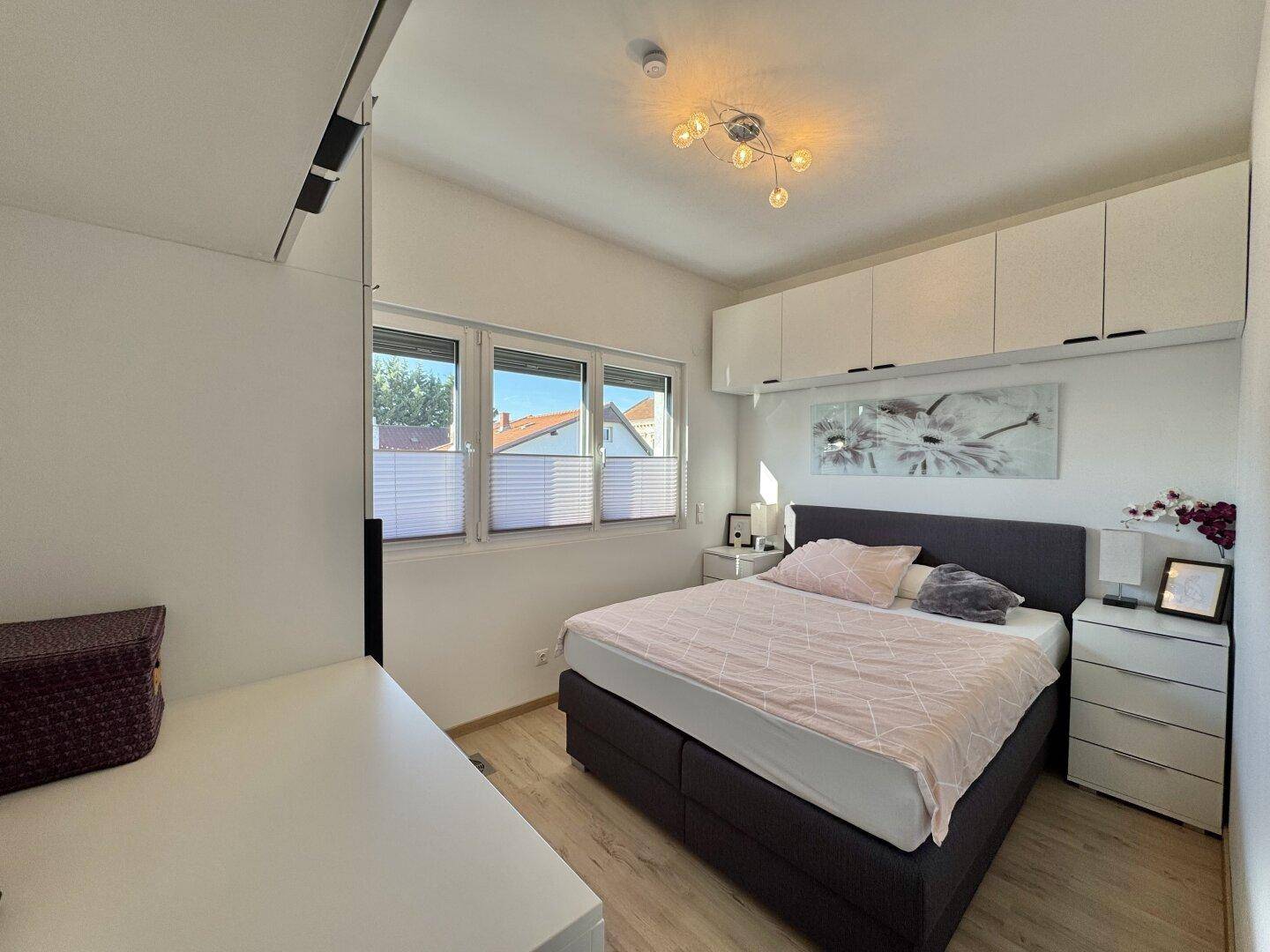 Helles Schlafzimmer mit Doppelbett, Nachttischen und praktischen Wandschränken für zusätzlichen Stauraum.
