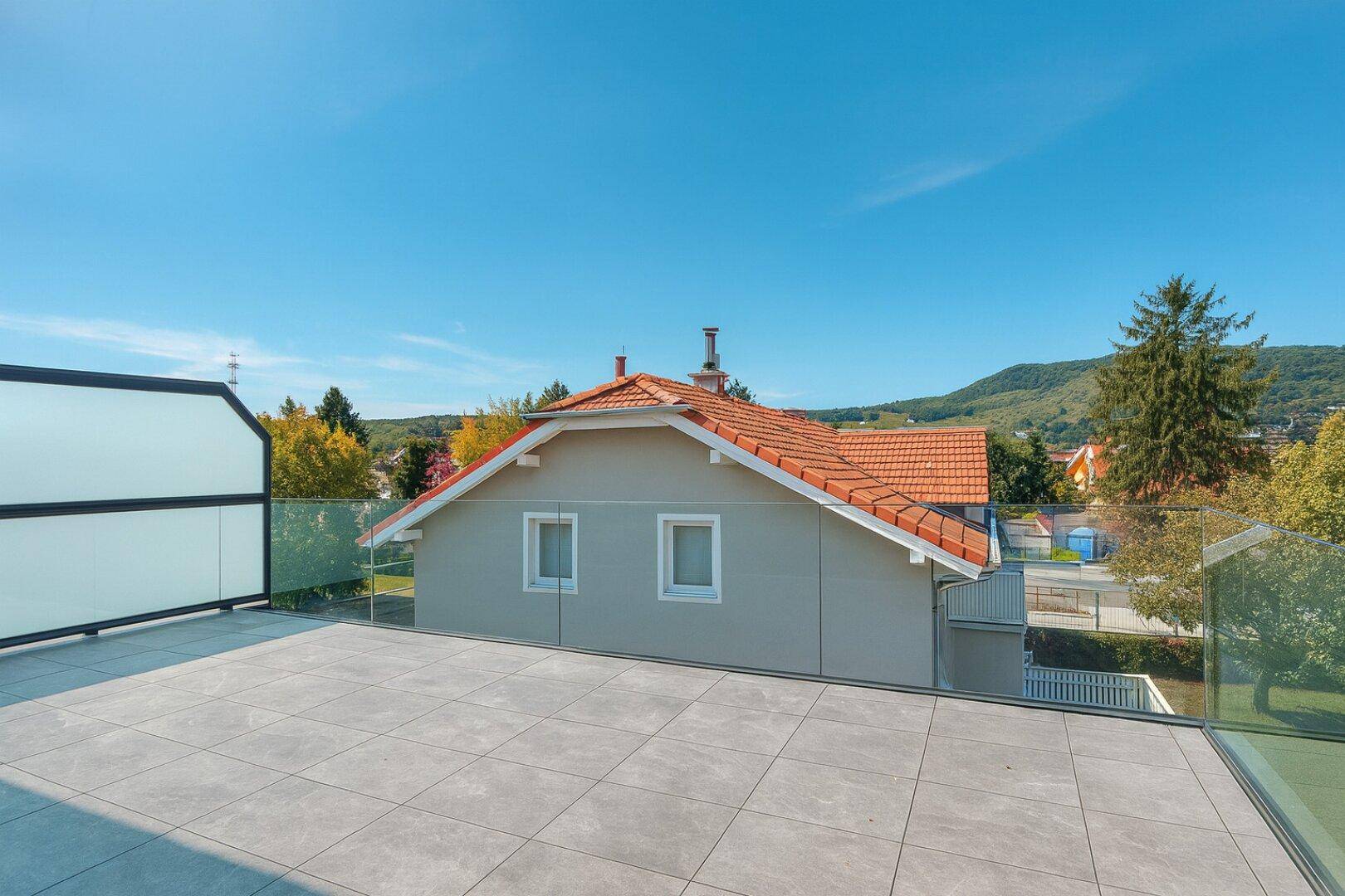 Weitläufige Dachterrasse mit Fliesenboden und Panoramablick auf die umliegende Landschaft.