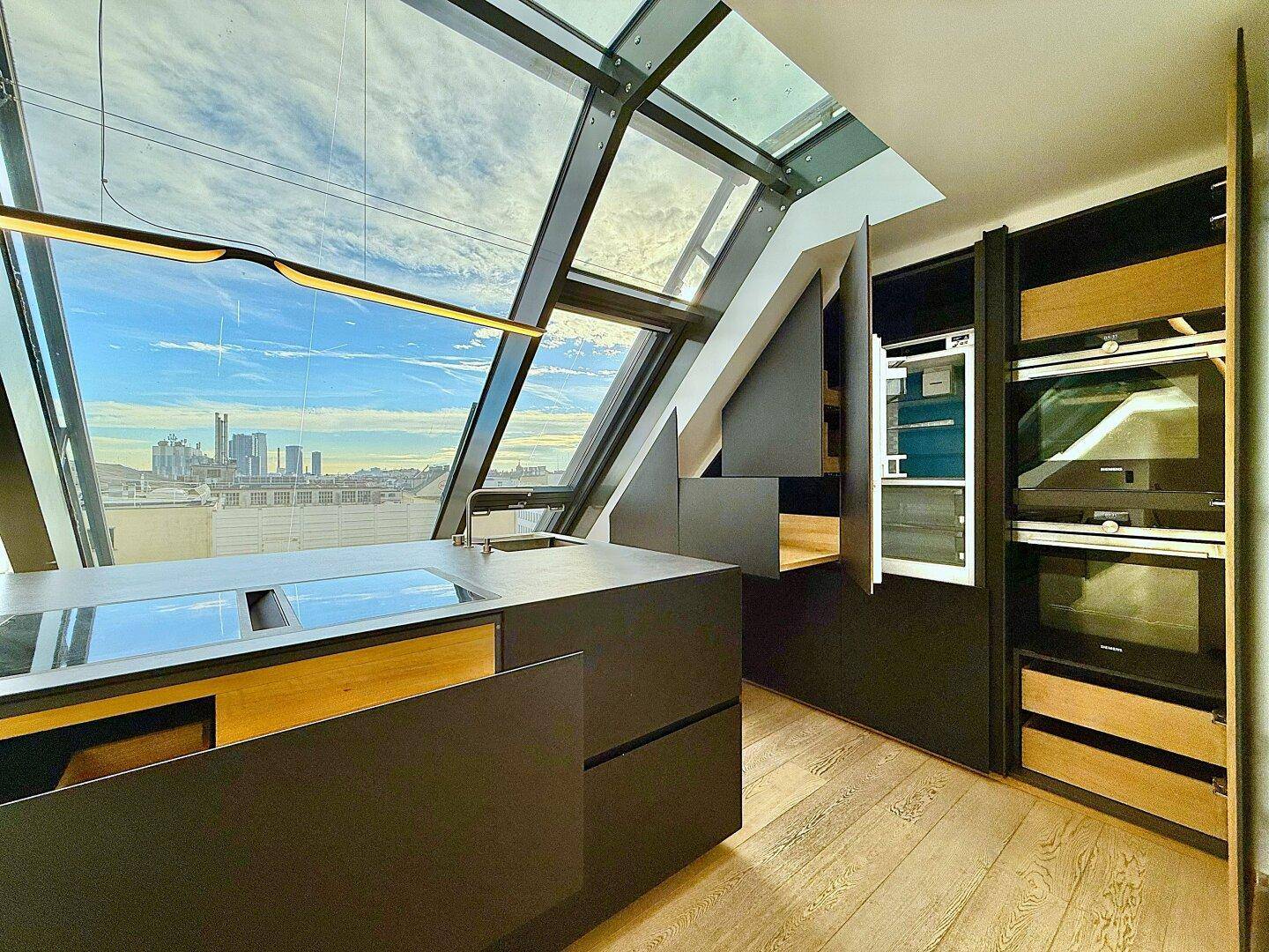Elegante Küche mit schwarzen Einbauschränken, modernen Geräten und einer weiten Glasfront mit Stadtpanorama.