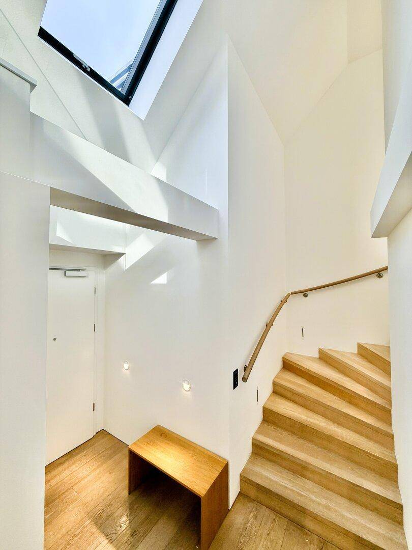 Heller Flur mit Holztreppe und Oberlicht, das den Raum mit natürlichem Licht durchflutet.