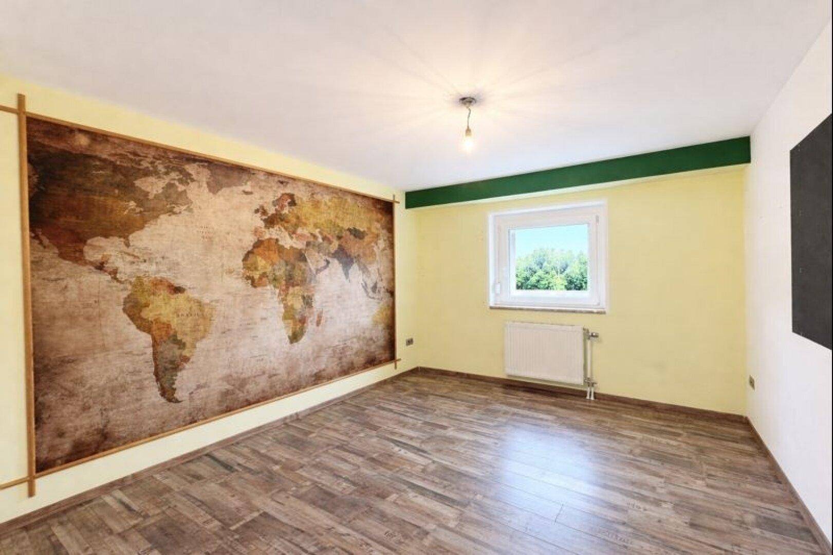 Schlafzimmer mit Weltkarten-Tapete, Holzboden und Fenster, ideal für Reiseliebhaber.