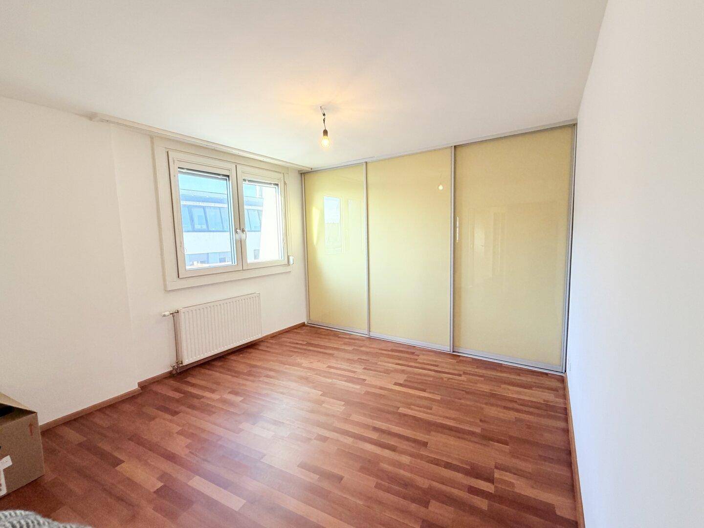 Leeres Zimmer mit Holzboden und praktischen Einbauschränken entlang einer Wand.