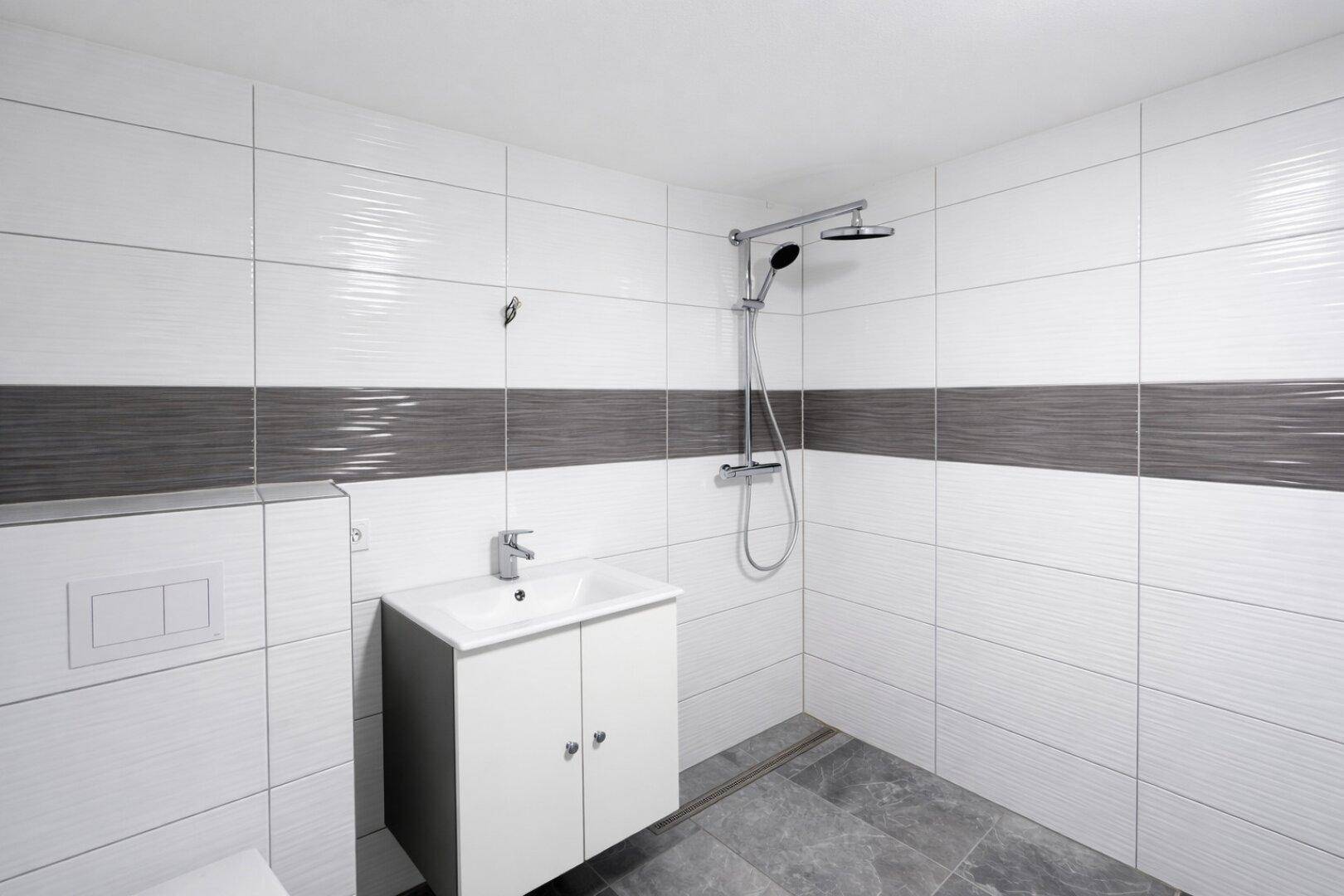 Modernes Badezimmer mit ebenerdiger Dusche, Einzelwaschbecken und Wand-WC.
