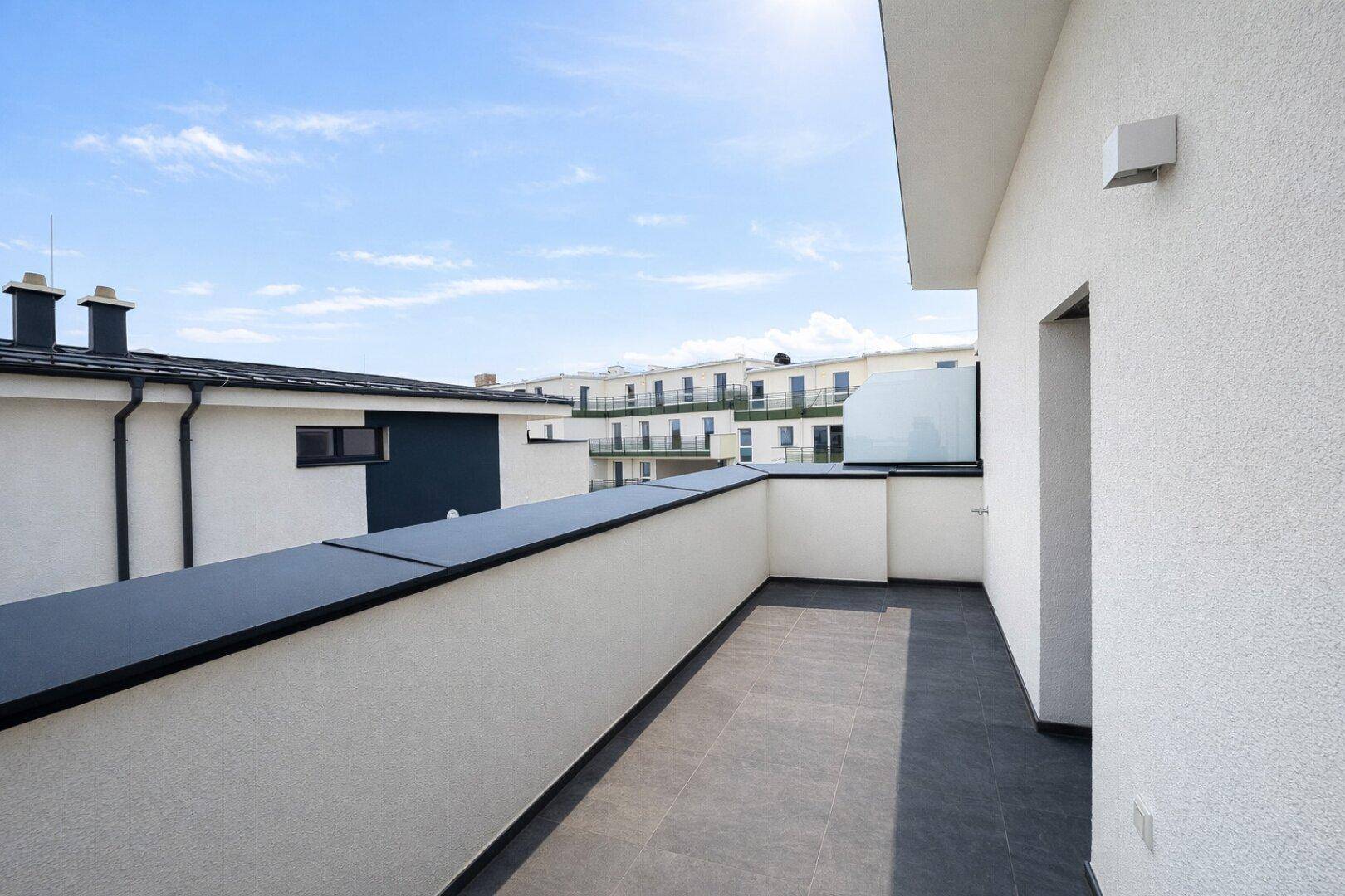 Geräumige Dachterrasse mit Fliesenboden und Glasgeländer, ideal zum Entspannen.