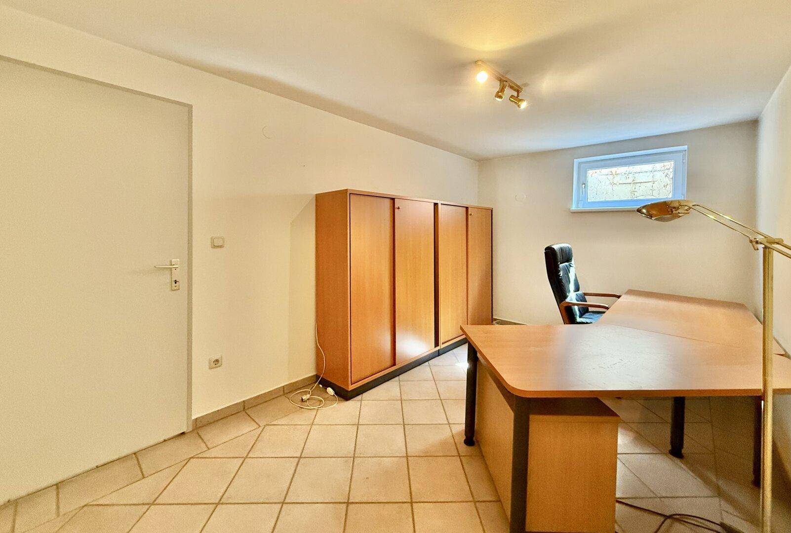 Helles Büro mit Holzschrank, Schreibtisch und Fliesenboden, ideal für Home-Office.