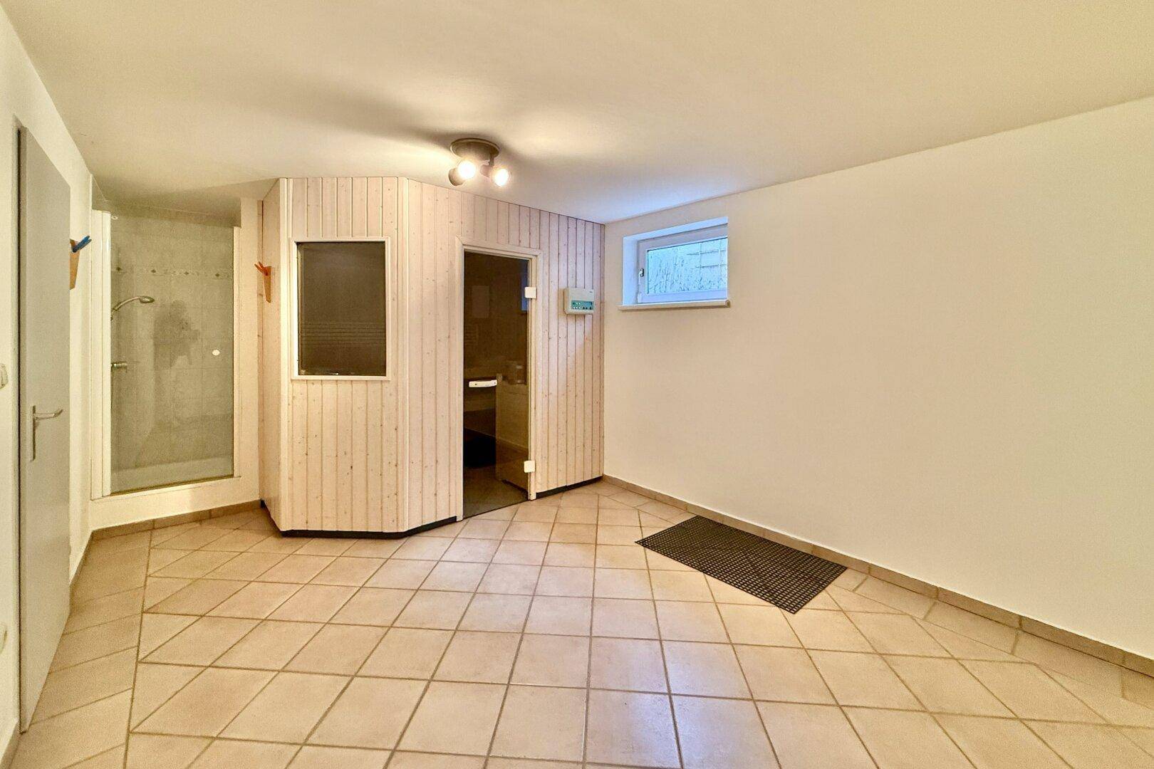 Raum im Untergeschoss mit Sauna, Dusche und Fliesenboden für Wellness-Momente.
