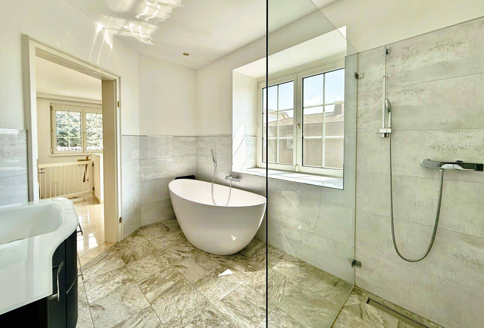 Modernes Badezimmer mit freistehender Badewanne, begehbarer Dusche und Fenster.