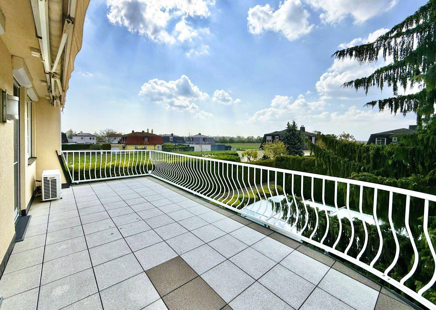 Großer Balkon mit Fliesenboden und weitem Blick über die umliegende Wohngegend.