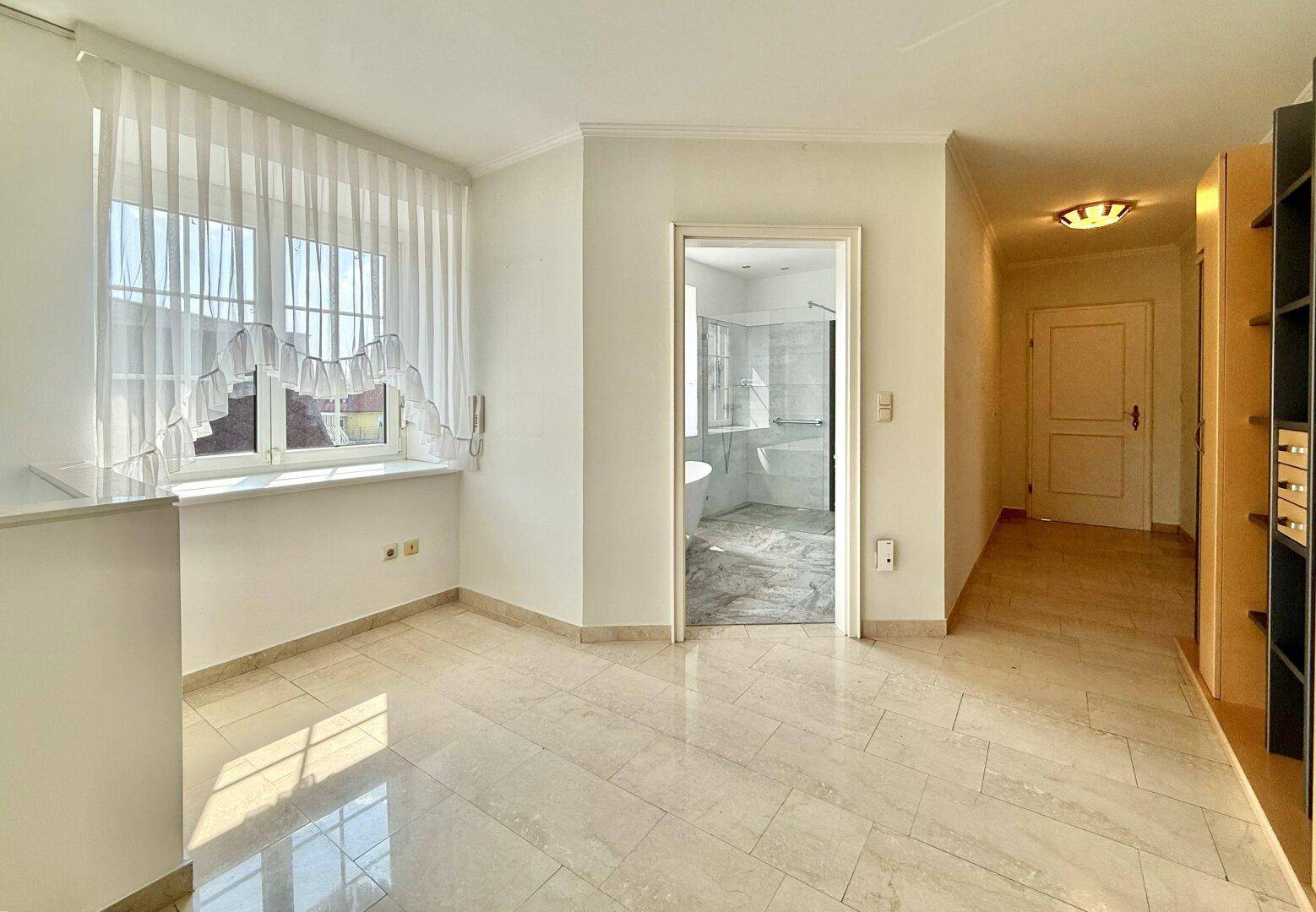 Heller Raum mit Marmorboden und offenem Zugang zu einem modernen Badezimmer.