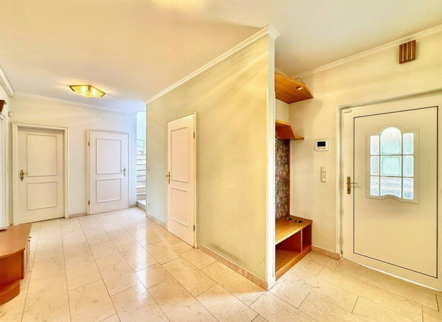 Heller Eingangsbereich mit Fliesenboden, Garderobe und Zugang zu weiteren Räumen des Hauses.