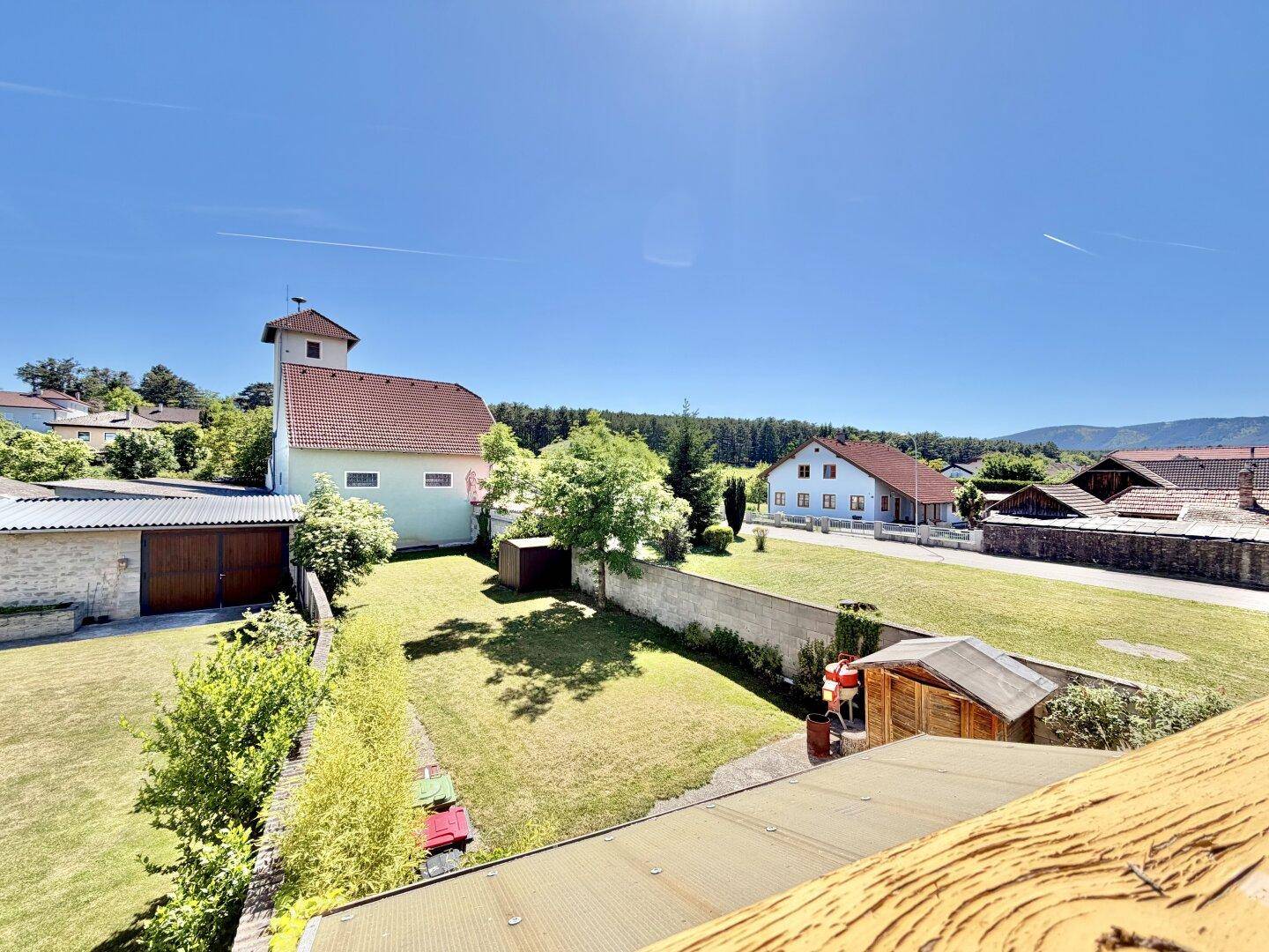Weitläufiger Blick über das Grundstück mit Garten, Nebengebäuden und umliegender Landschaft.