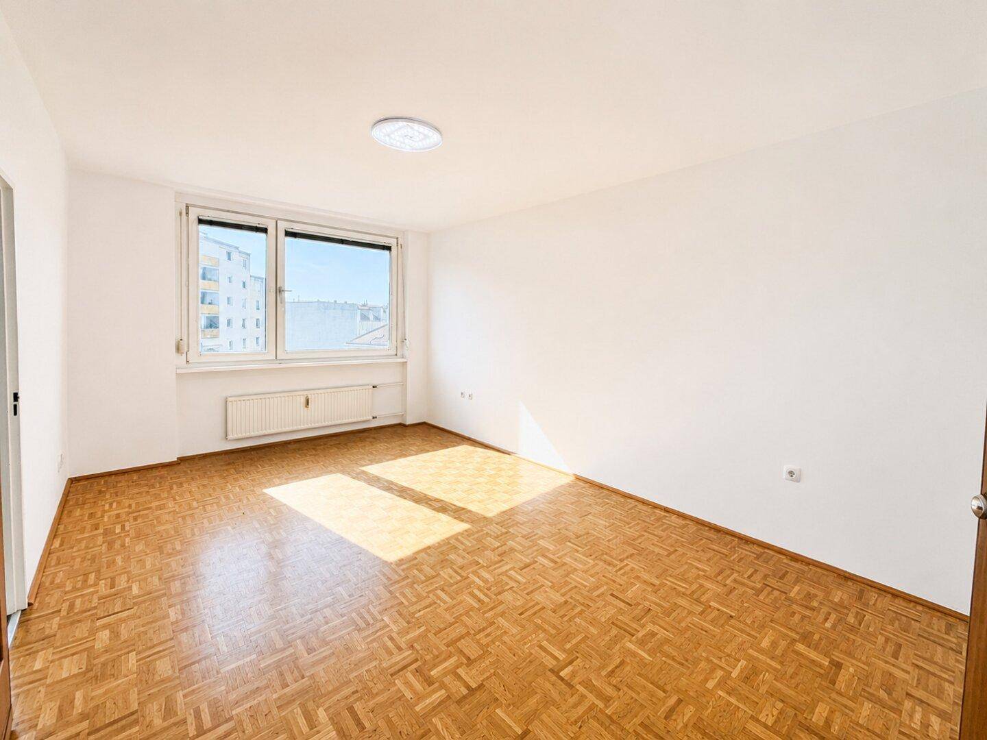 Geräumiger, leerer Raum mit Parkettboden und großen Fenstern für viel Helligkeit.