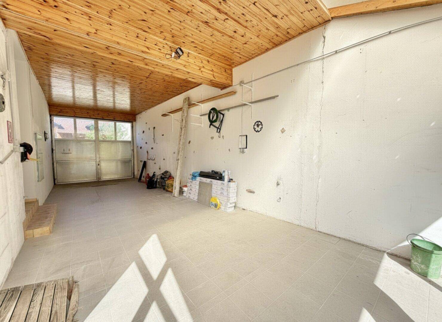 Geräumige Garage mit Holzbalkendecke und ausreichend Platz für Fahrzeuge und Lagerung.