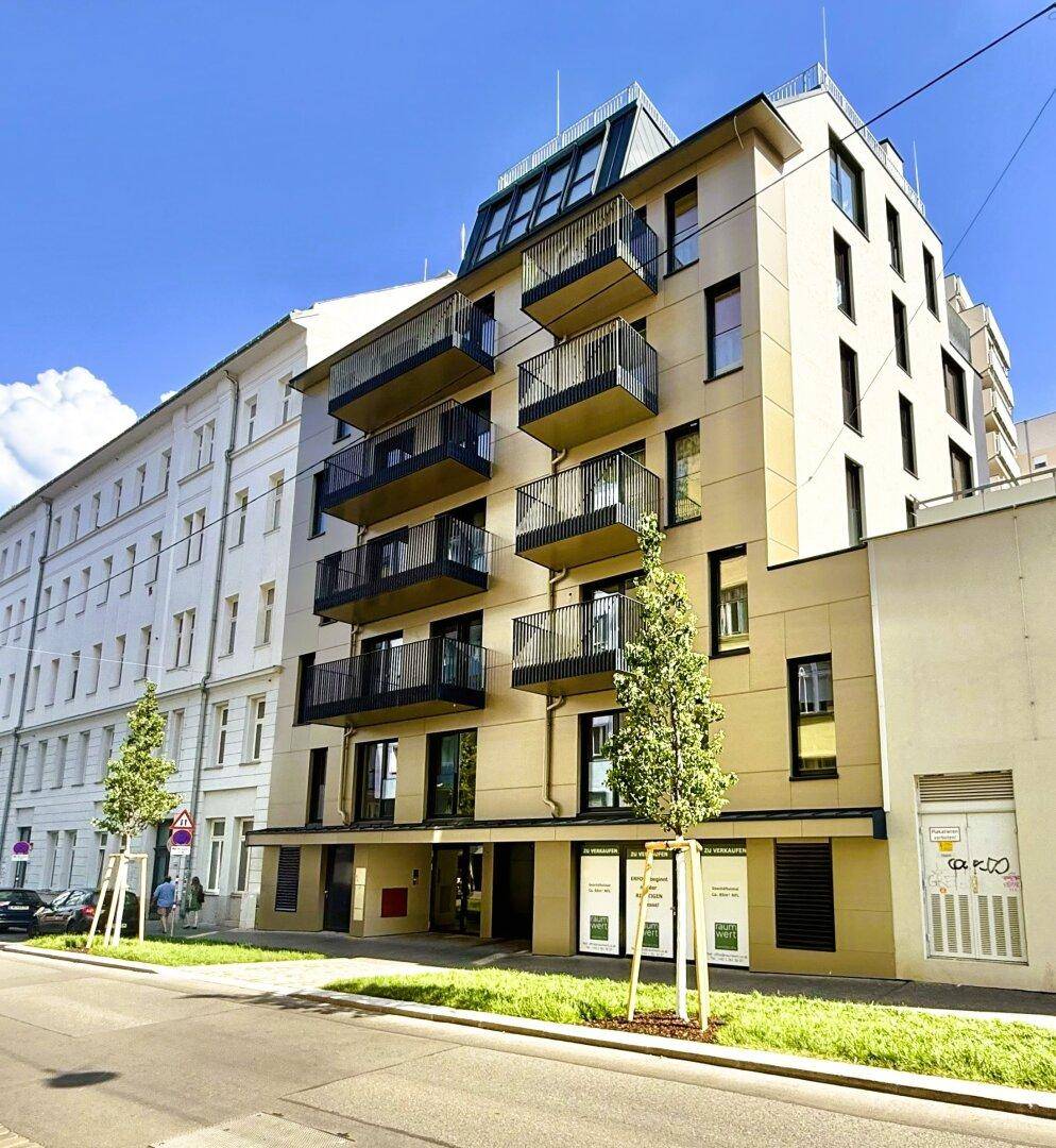 Modernes Mehrfamilienhaus mit mehreren Balkonen an einer städtischen Straße.