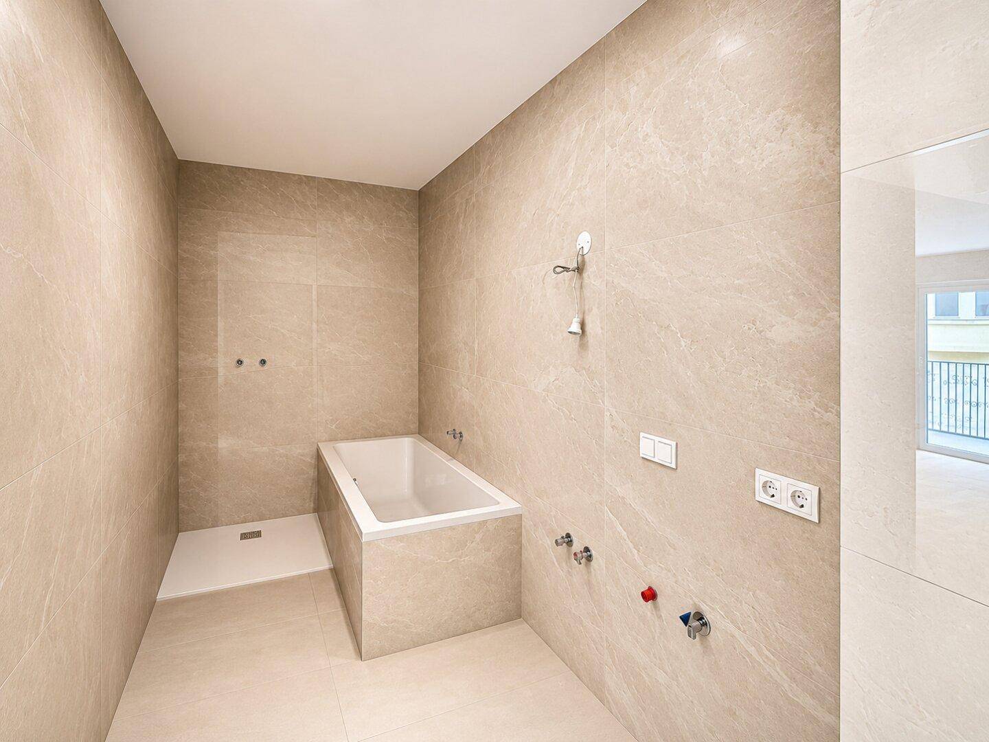 Unmöbliertes Badezimmer mit Duschbereich und Badewanne, bereit für die Installation.