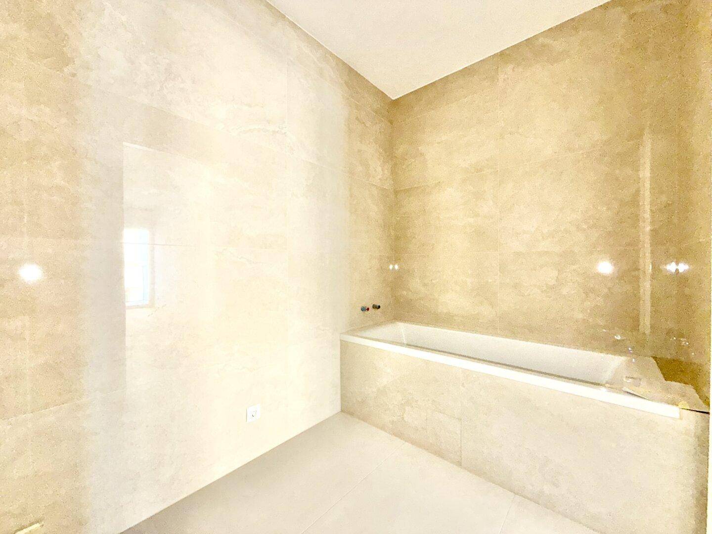 Elegantes Badezimmer mit beigefarbenen Fliesen und einer integrierten Badewanne.