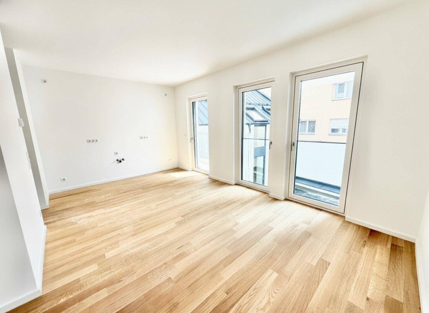 Heller, leerer Wohnbereich mit Holzparkett und großen Fenstern, bereit zur individuellen Gestaltung.
