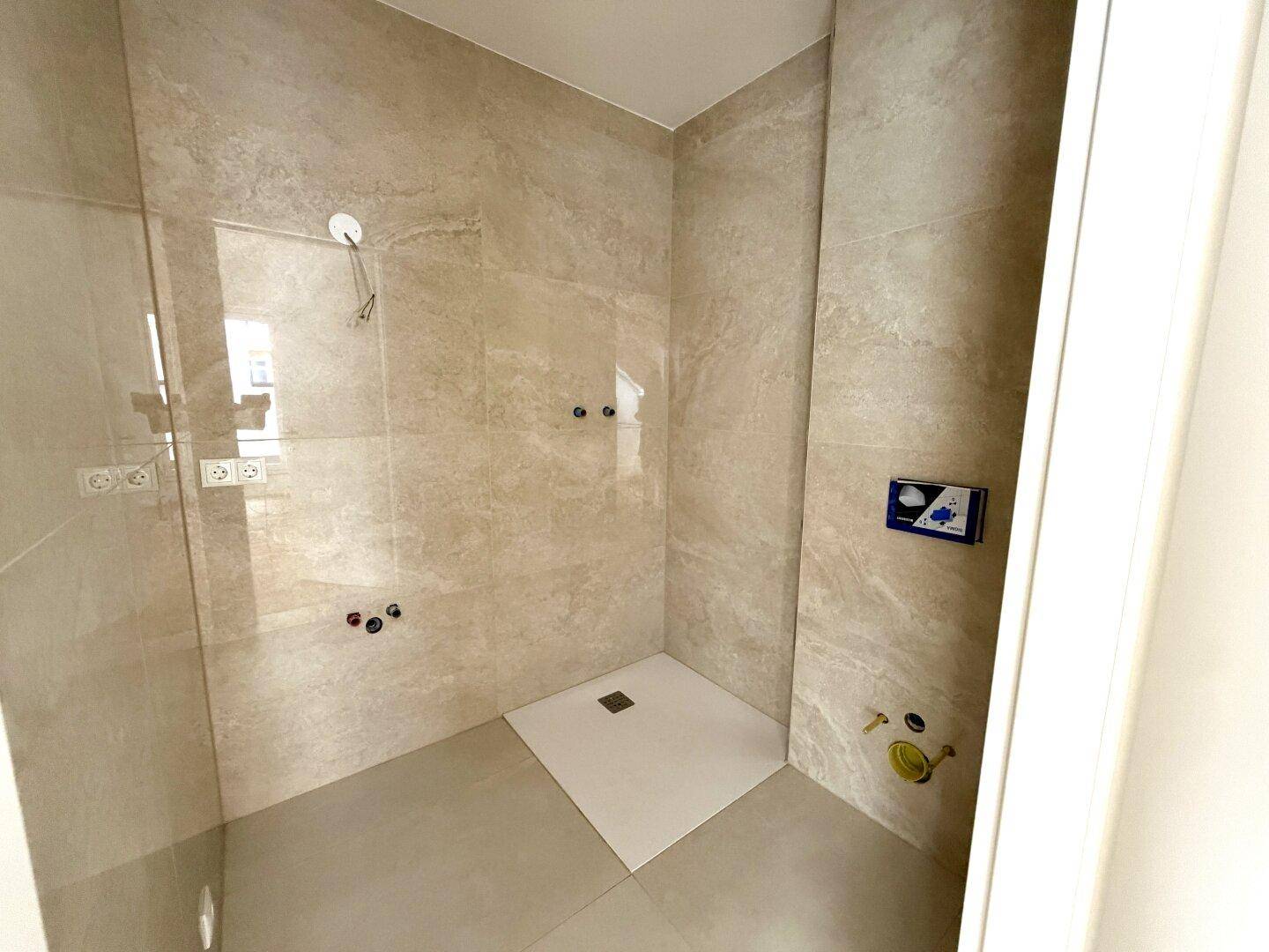 Modernes Badezimmer im Bau mit begehbarer Dusche und großformatigen Fliesen.
