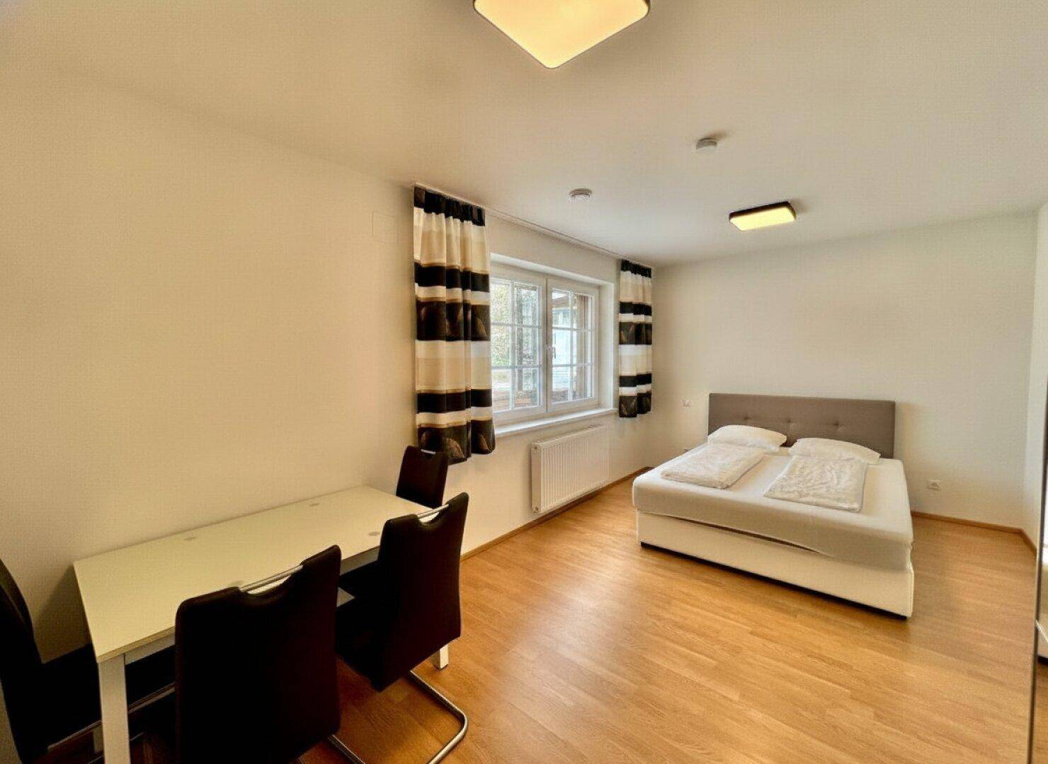 Vielseitiger Raum mit Bett und Esstisch, ideal als Gästezimmer oder Büro.