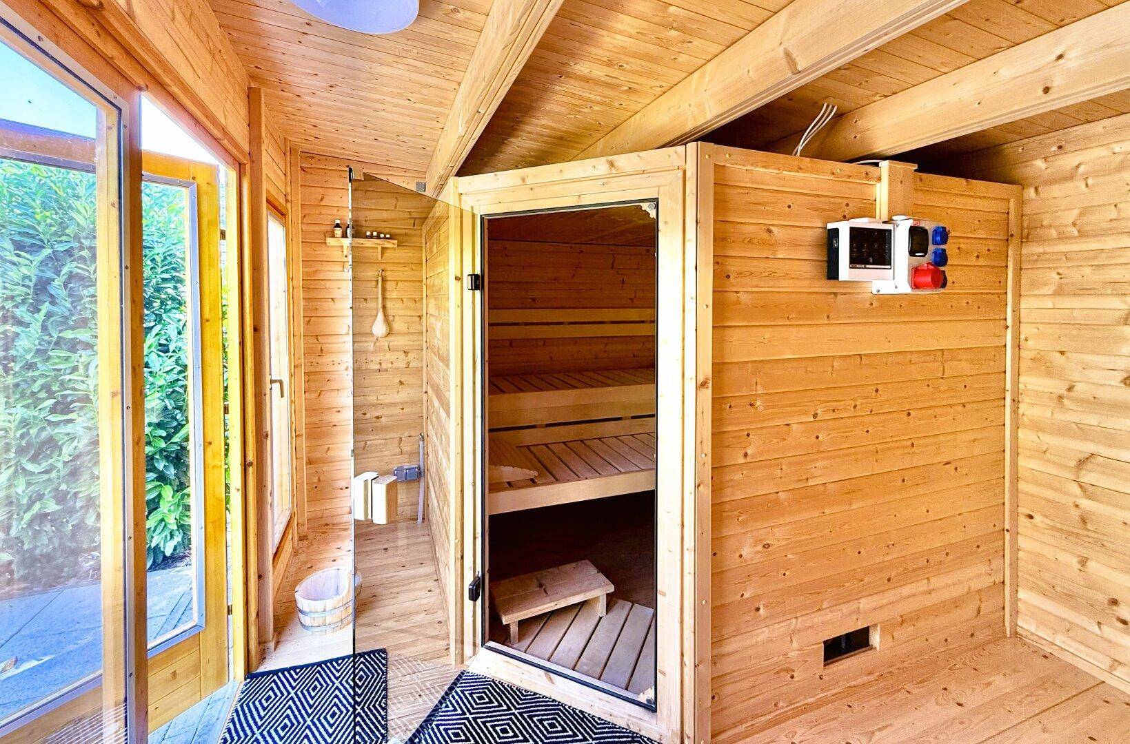 Wellnessbereich mit Holzsauna und Dusche, ideal zur Entspannung nach einem langen Tag.