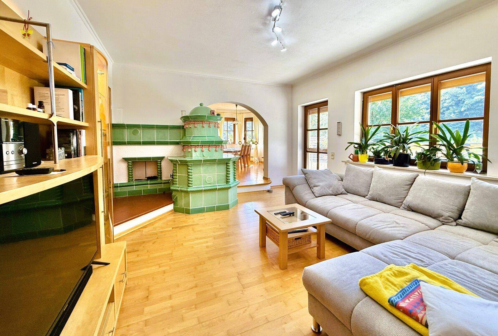 Gemütliches Wohnzimmer mit Kachelofen, Holzboden und bequemer Sofalandschaft.