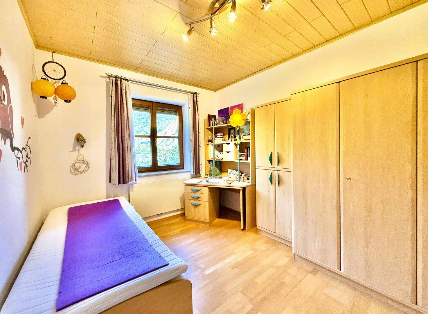 Kinderzimmer mit Holzboden, Schreibtisch und Kleiderschrank, bereit zum Einzug.