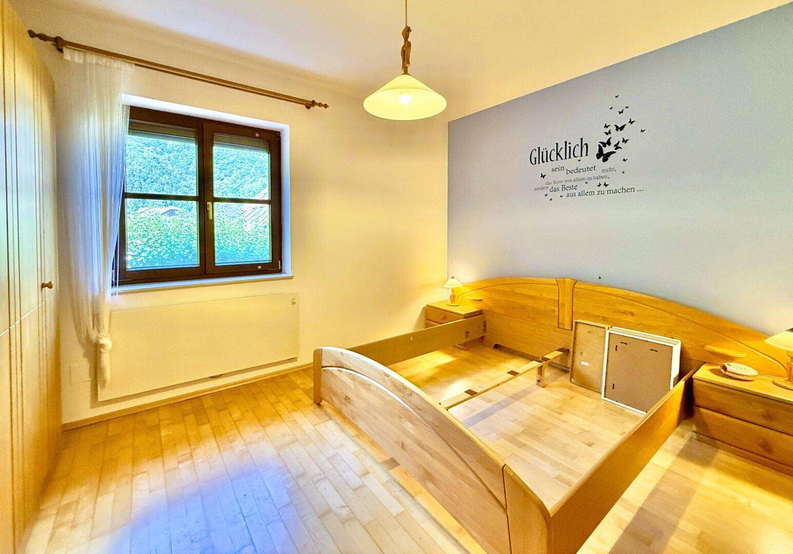 Helles Schlafzimmer mit Holzboden und Wandtattoo, bereit für die Einrichtung.