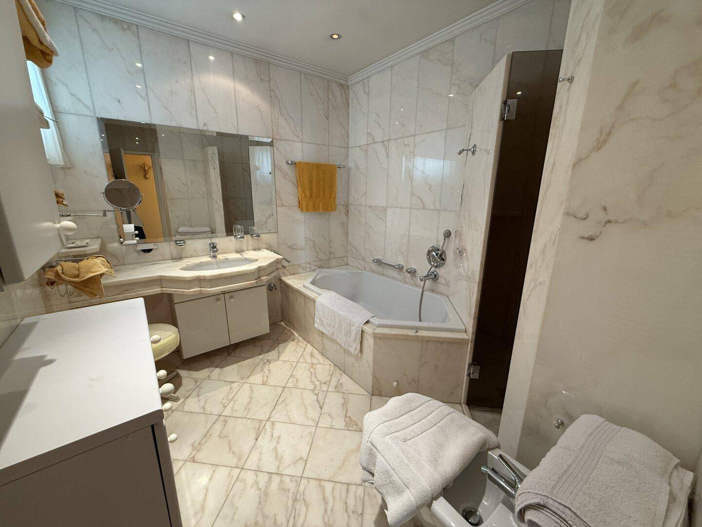 Marmoriertes Badezimmer mit Eckbadewanne, Doppelwaschbecken und Bidet in klassischem Stil.