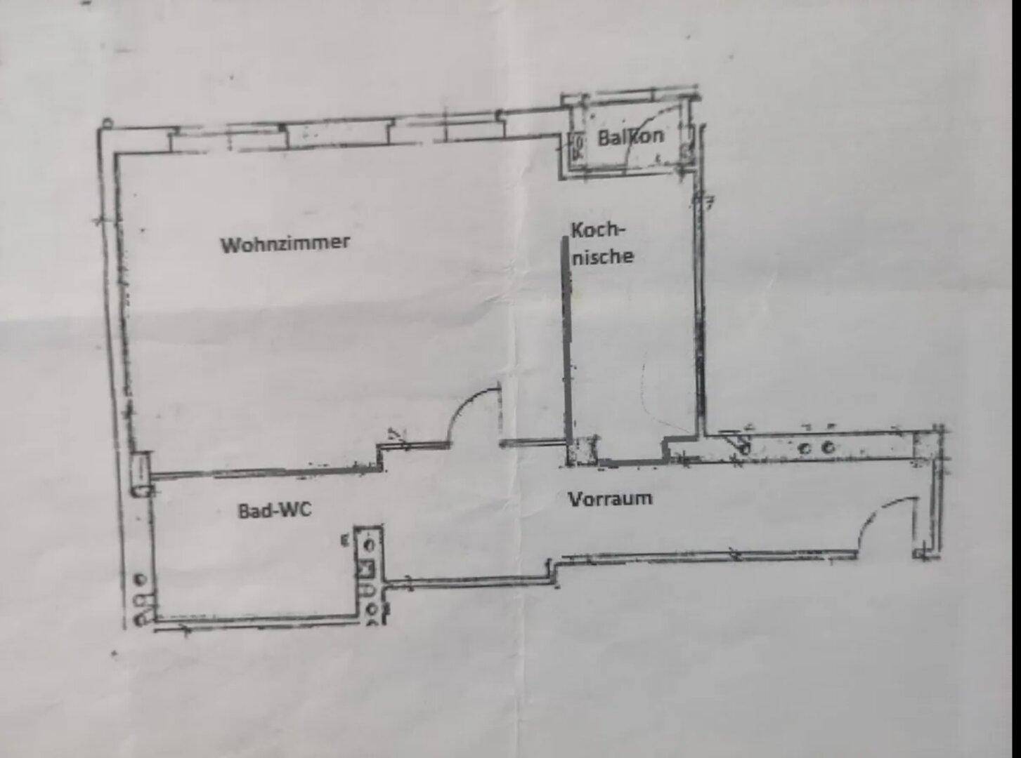 Handgezeichneter Grundriss einer Wohnung mit Wohnzimmer, Kochnische, Bad-WC und Balkon.