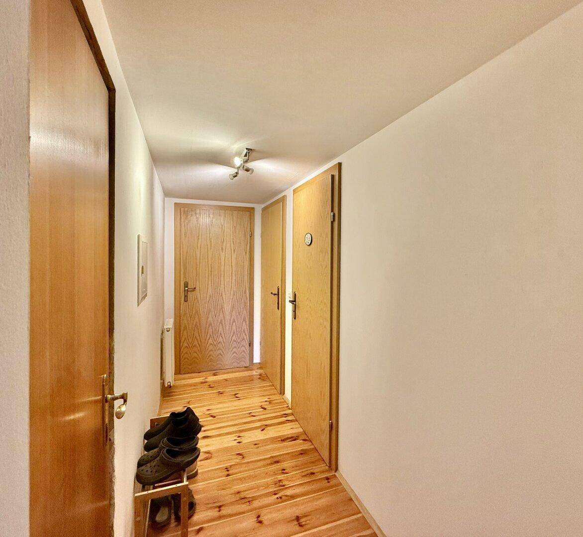 Flur mit Holztüren und Dielenboden, der zu verschiedenen Räumen führt.