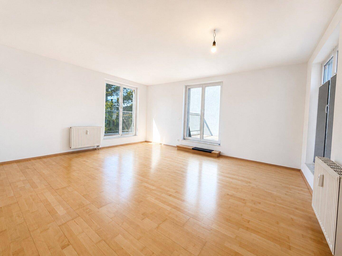 Geräumiger, leerer Raum mit hellem Holzboden und großen Fenstern, ideal für individuelle Gestaltung.